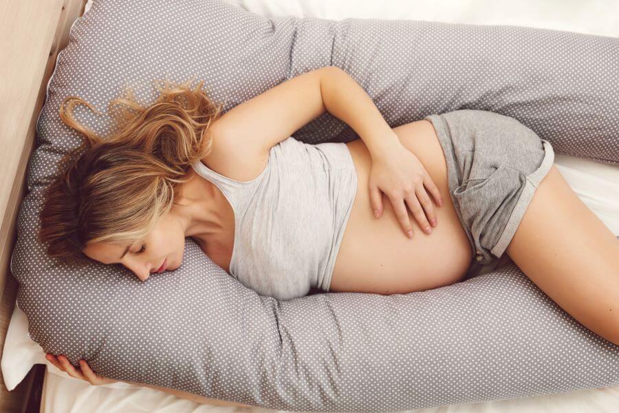 Schwangere schläft mit Stillkissen